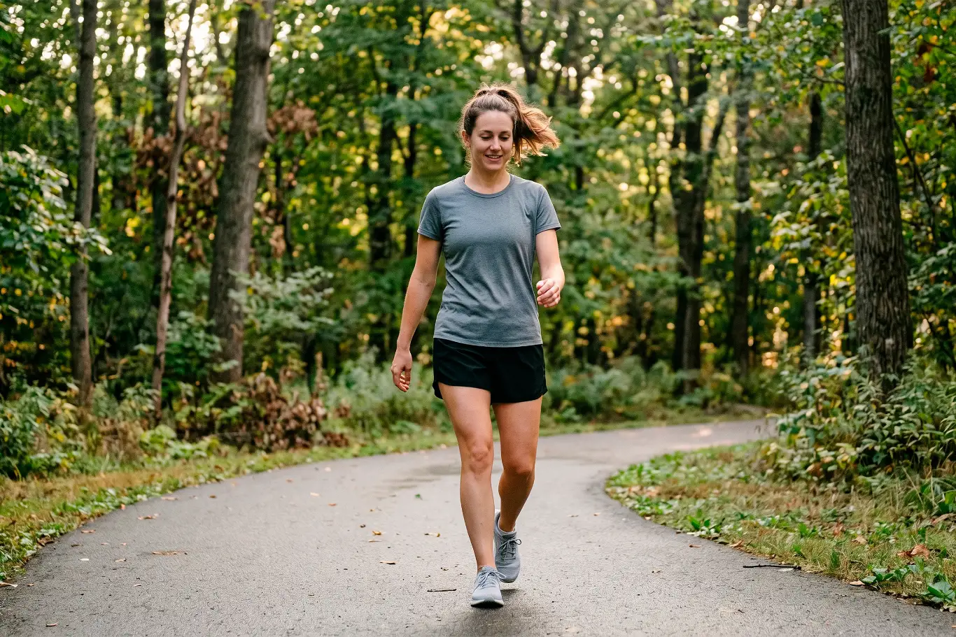 Woman walking on a scenic forest path wearing athletic clothing